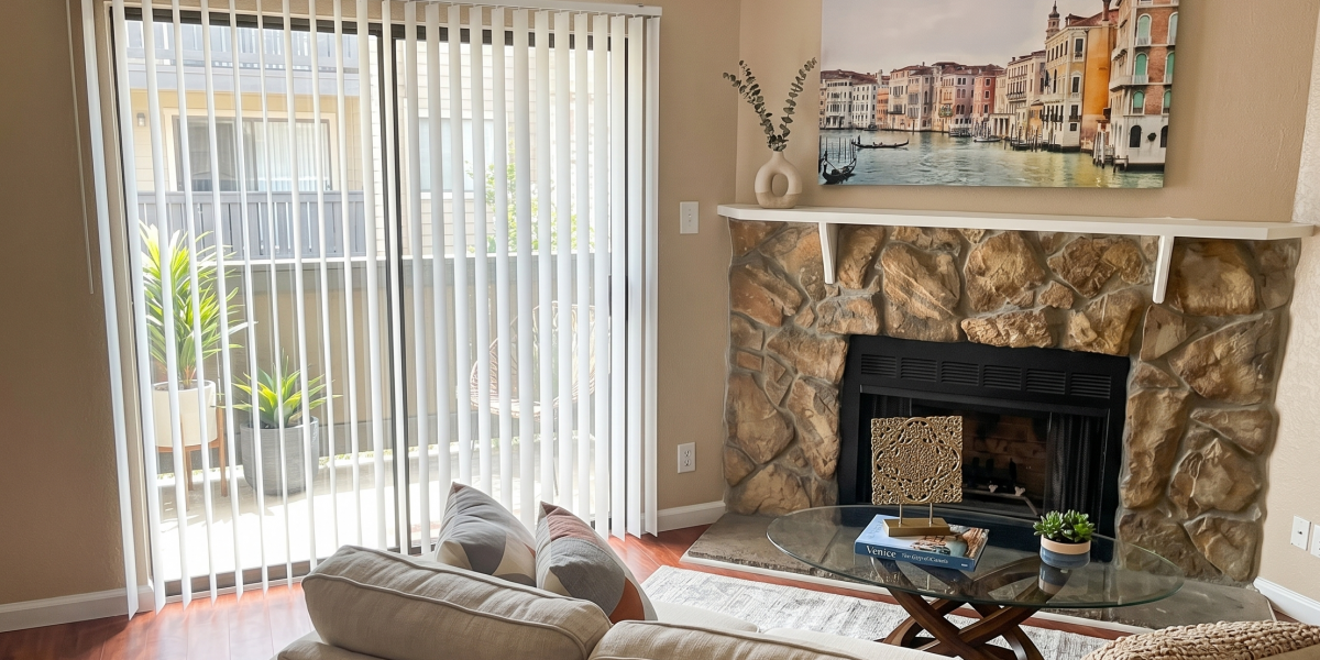 Furnished living room with a stone fireplace and sliding door to a private patio at Falls of Wilcrest